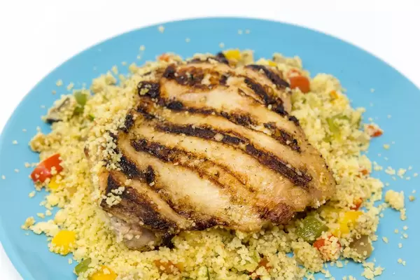 Nahaufnahme von arabisch gegrilltem Hühnchen auf Couscous mit Gemüse an Razel Hanout Dip