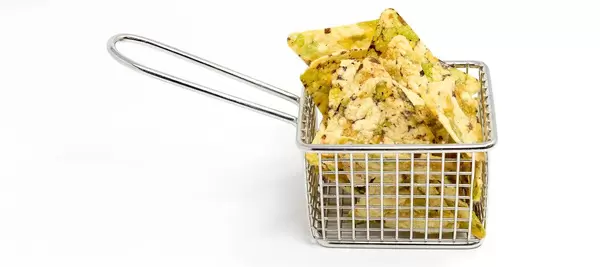 Nahaufnahme von bunten, veganen Chips "Vaya Bohnen-Salz-Snack" von Zweifel, in einem Frittierkorb