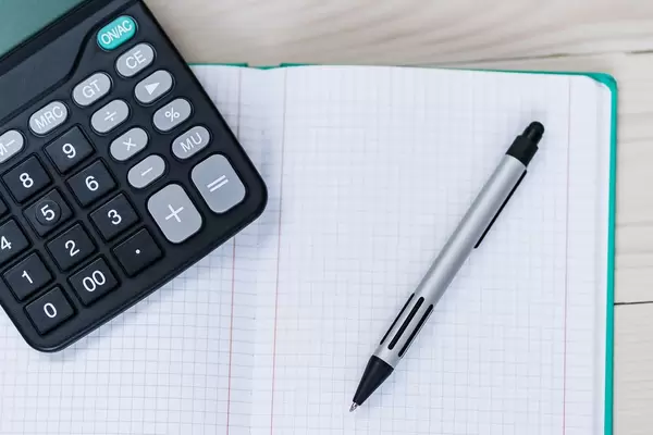 Nahaufnahme von einem Notizheft mit Taschenrechner und Stift