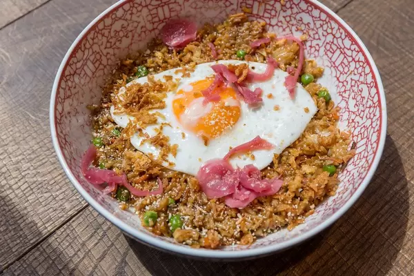 Nahaufnahme von einem vegetarischen Gericht mit gebratener Reis, Erbsen, Karotten, Zwiebeln, Chili, Knoblauch und Spiegelei