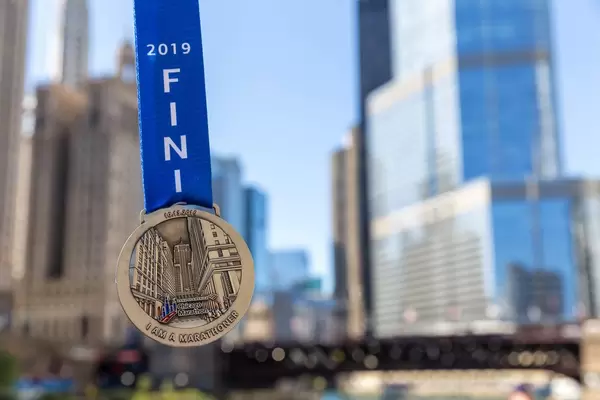Nahaufnahme von einer Medaille für Teilnehmer vom 2019 Chicago Marathon mit Wolkenkratzern im Hintergrund