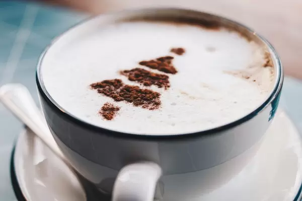 Nahaufnahme von einer Tasse Cappuccino mit Kakao in Weihnachtsbaum-Gestalt