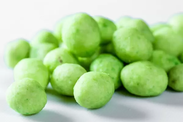 Nahaufnahme von Erdnüssen in Wasabi vor weißem Hintergrund