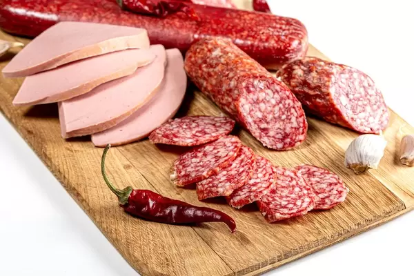 Nahaufnahme von geräucherter Salami und anderen Wurstwaren auf einem Küchenbrettchen aus Holz