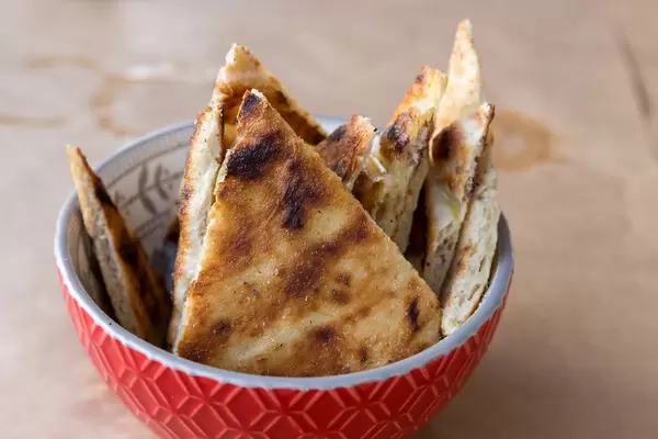 Nahaufnahme von geschnittenem Pitabrot in einer roten Schale auf einem Tisch