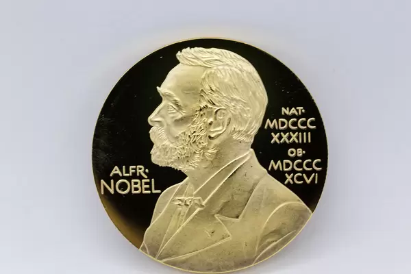 Nahaufnahme von Goldmedaille mit Porträt von Alfred Nobel vor weißem Hintergrund
