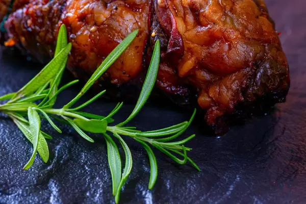 Nahaufnahme von Hackbraten mit Rosmarinzweig vor dunklem Hintergrund