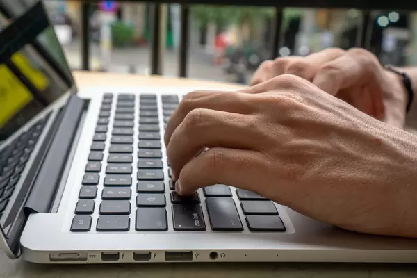 Nahaufnahme von  Händen auf Laptop Tastatur- digitaler Nomade arbeitet online