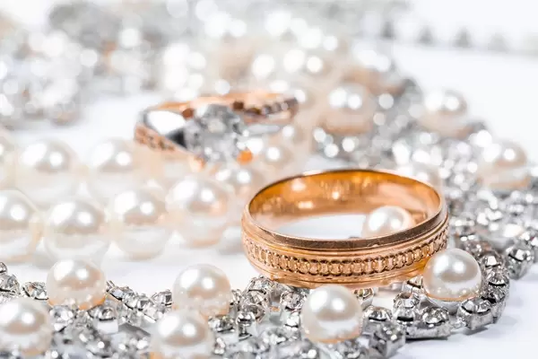 Nahaufnahme von Hochzeitsringen und der Brautkette mit weißen Perlen