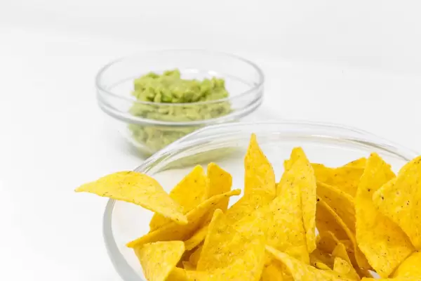 Nahaufnahme von Nacho Chips mit Guacamole Avocado Dip im Hintergrund