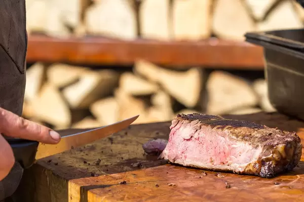 Nahaufnahme von noch leicht blutigem, frisch geschnittenem Stück Grillfleisch auf Holztisch