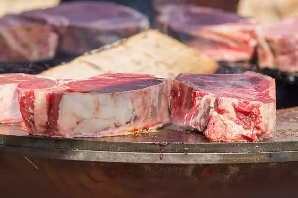 Nahaufnahme von noch rohen, saftigen Koteletts auf OFYR Grillplatte am Tomorrowland Festival 2019