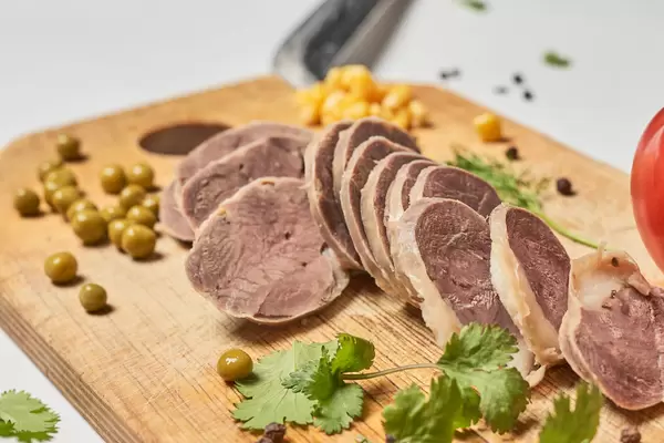 Nahaufnahme von Pferdefleisch auf einem Holzbrett mit Oliven und Kräutern. Kazy Wurst aus Usbekistan