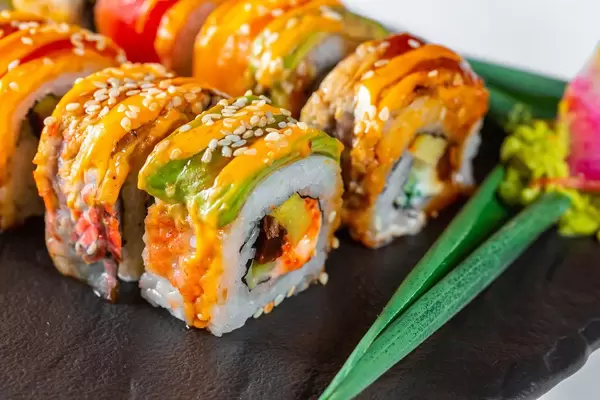 Nahaufnahme von Portion Sushi mit Lachs, Sesam und Käse serviert mit Wasabi