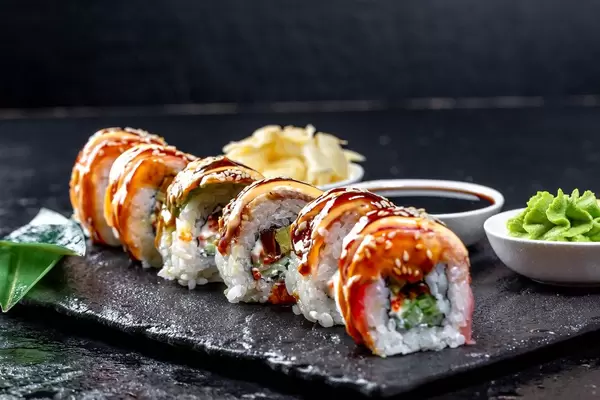 Nahaufnahme von Rainbow Dragon Sushi Rollen auf schwarzem Tablett