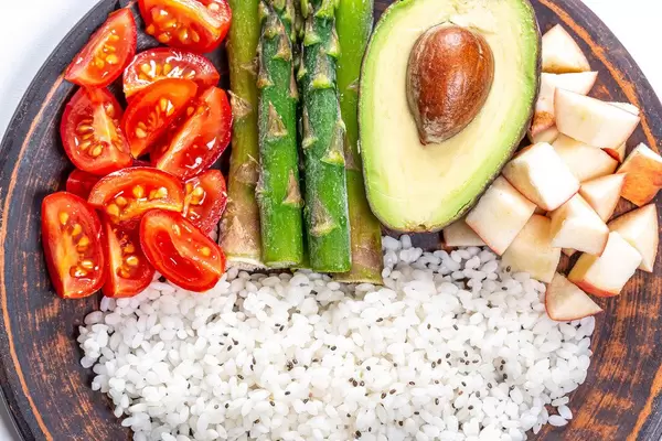 Nahaufnahme von Reis mit Chiasamen, Obst und Gemüse auf einem Bambusteller