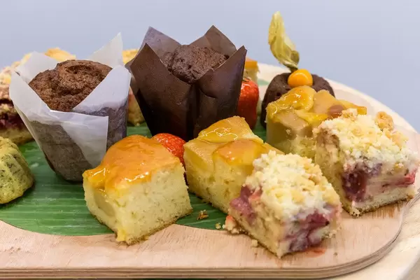 Nahaufnahme von Schokoladenmuffins und verschiedenen Stücken Obstkuchen auf einem Küchenbrett am Büfetttisch des AXA Barcamps OMWest 2019 in Köln