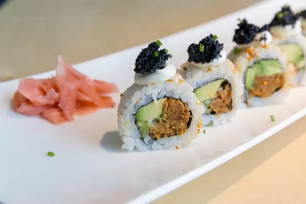 Nahaufnahme von Sushi für veganer, mit pflanzlichen Lebensmitteln wie Avocado, Frühlingszwiebeln, veganes Tonno, veganer Kaviar und würzige Soße