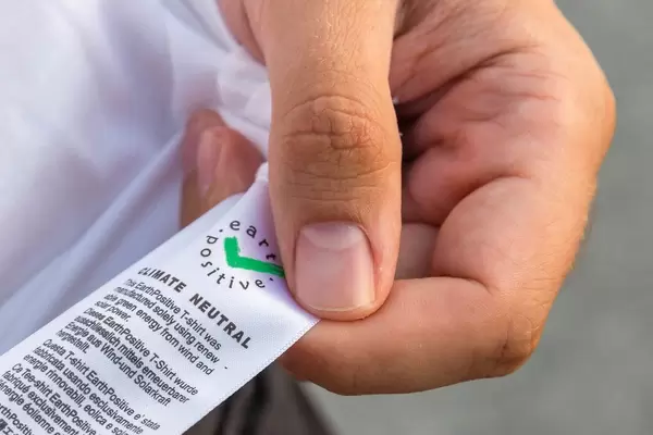 Nahaufnahme von T-Shirt-Etikett der Marke earth positive, die klimaneutrale Kleidung herstellt