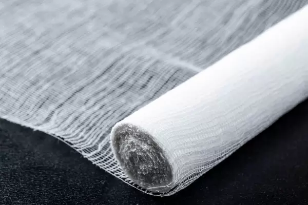 Nahaufnahme von teilweise aufgerollter Bandage oder Verband auf dunklem Hintergrund