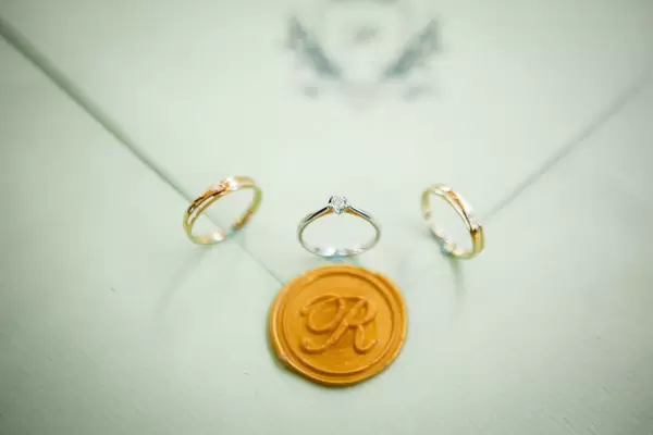 Nahaufnahme von Trauringen und Verlobungsring um Wachssiegel der Hochzeitseinladung