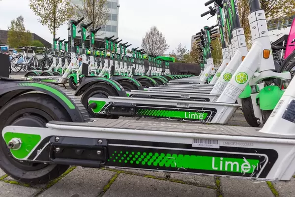 Nahaufnahme von unten: viele ordentlich geparkte Lime E-Scooter in Köln