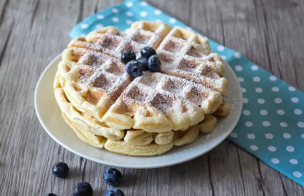 Nahaufnahme von Waffeln mit Puderzucker und Heidelbeeren