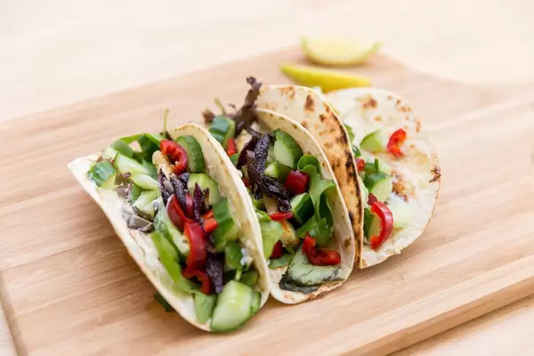 Nahaufnahme von würzig-feurige Halloumi-Tacos mit roter Zwiebel, roter Chili, Gurke und Salatmischung