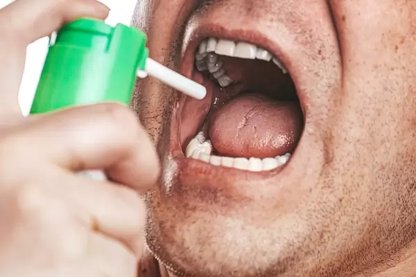 Nahaufnahme zeigt einen Mann beim Benutzen von Mundspray für eine saubere Mundhygiene