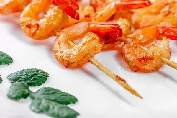 Nahaufnahme zeigt knusprige, gegrillte Shrimps, auf Holzstäben aufgespießt