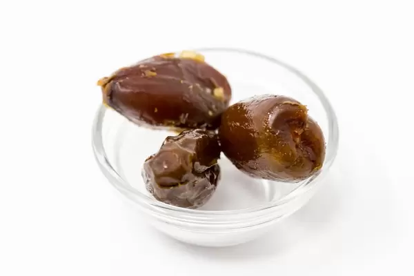 Nahaufname von drei frischen Datteln in einer Glasschale