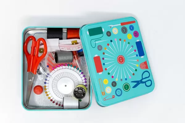 Nähset mit Nadeln, Faden, Schere, Fingerhut, Maßband und Knöpfen in türkisen Metallbox
