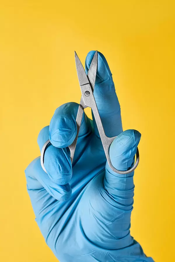 Nail artist holds a tinny scissor