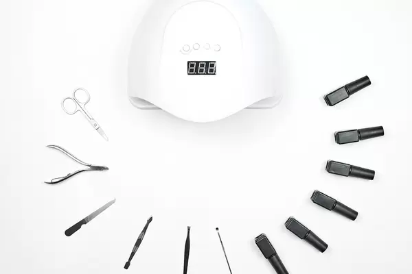 Nail LED lamp, gel polishes and set of tools for manicure on white table