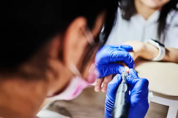 Nail master remove nail polish in beauty salon with special electric machine