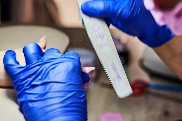 Nail tech filing nails with nail file