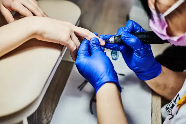 Nail technician using portable electric nail drill machine