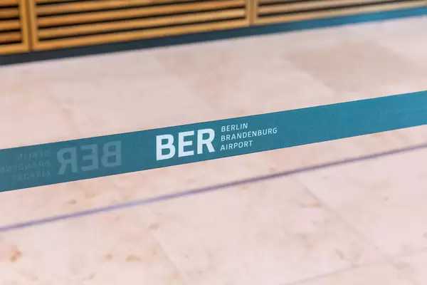 Name logo of the "BER Berlin Brandenburg Airport" on a blue-green queue line divider at the new airport