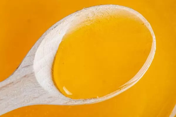 Natural bee honey in wooden spoon, top view