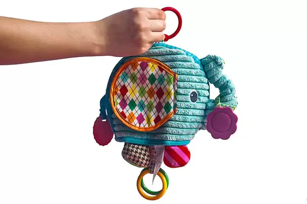 Natural cotton elephant rattle in mother's hand isolated on white background