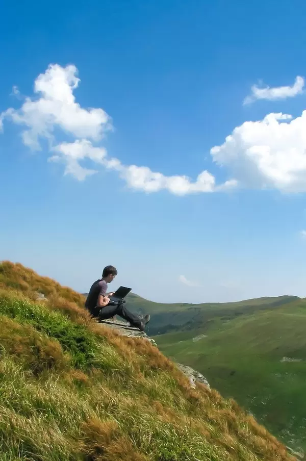 Nature Landscape Photo of Person Working on Laptop in Mountain Area with Blue Sky