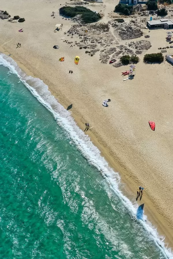 Naxos: drone photo of uncrowded sandy beach of Mikri Vigla with windsurfers resting and flying kites