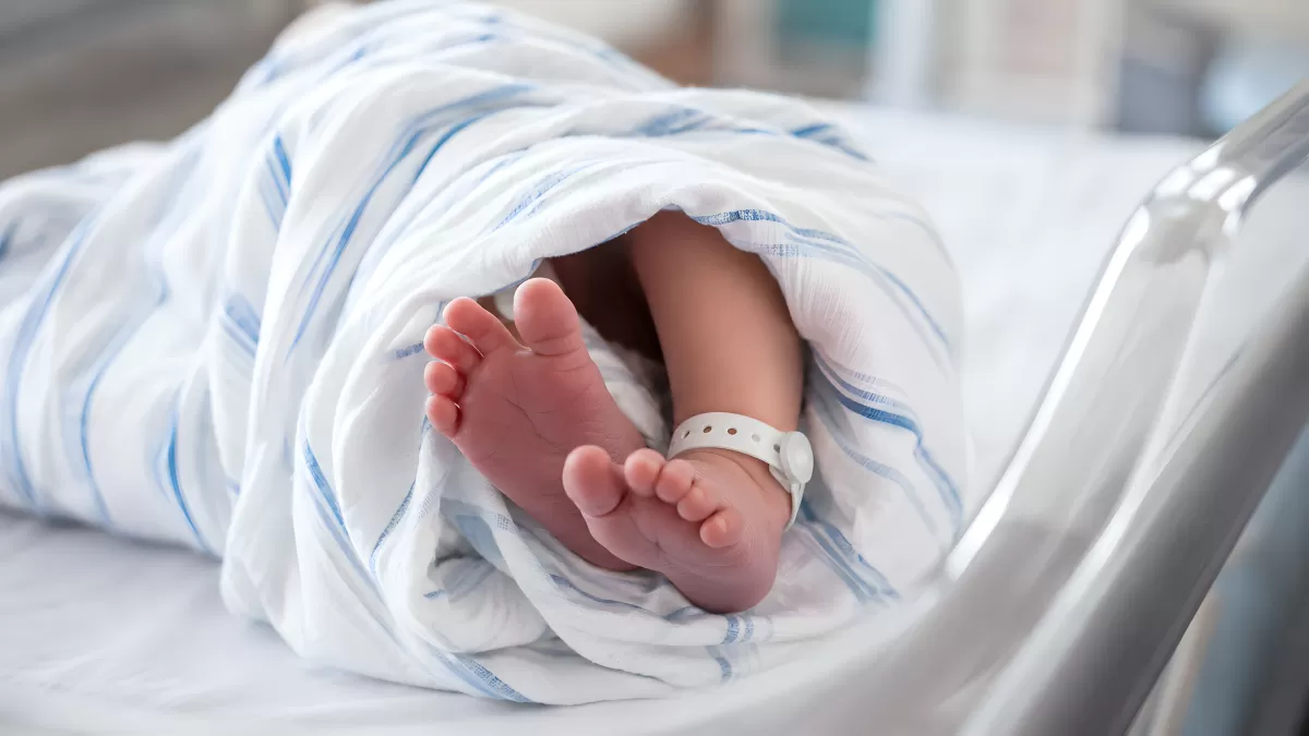 Neugeborenes Baby mit Krankenhaus-Armband im Bettchen