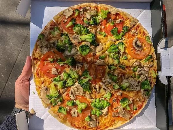New vegan Pizza "Kap Verde" from Dominos, with broccoli, tomatoes, fresh mushrooms, vegan processed cheese