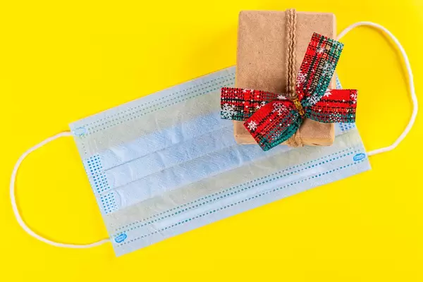 New year gift with a medical mask on a yellow background
