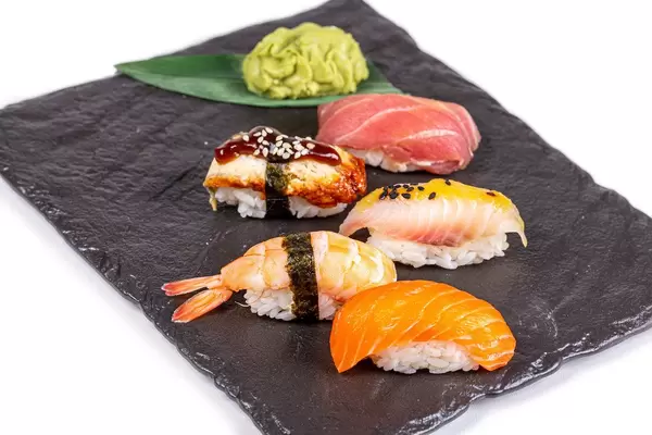 Nigiri with seafood on a black stone tray with wasabi