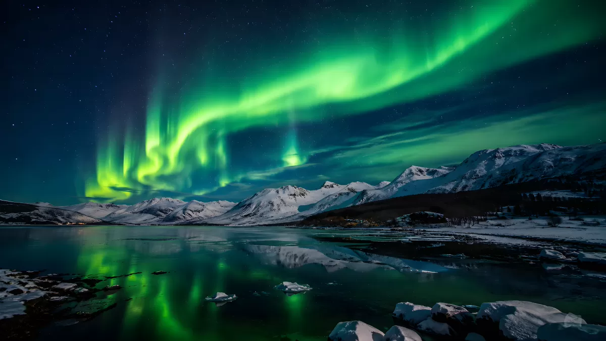 Nordlichter über verschneiten Bergen am Fjord