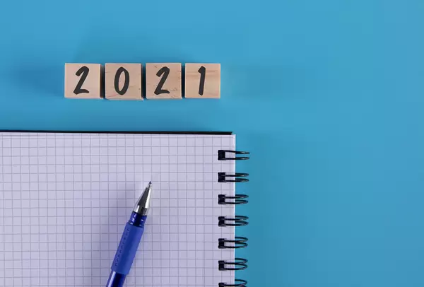 Notebook, pen and wooden cubes with 2021 text on blue background
