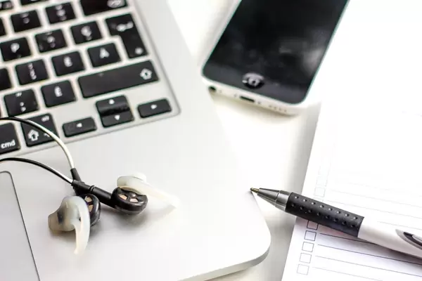 Notebook-Tastatur, Stift, Kopfhörer, Handy und Notizbuch