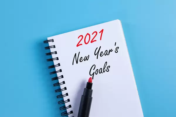 Notebook with 2021 New Year's Goals text on blue background
